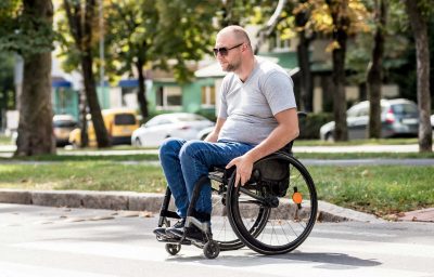 man in wheelchair crossing street road.