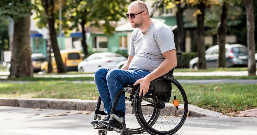 man in wheelchair crossing street road.