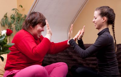 Two women, one of them disabled, making rhythm exercises