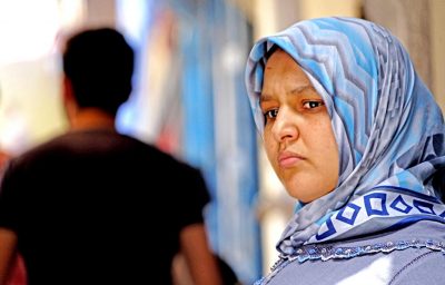 Arab woman with the colored veil of blue in a medina alley