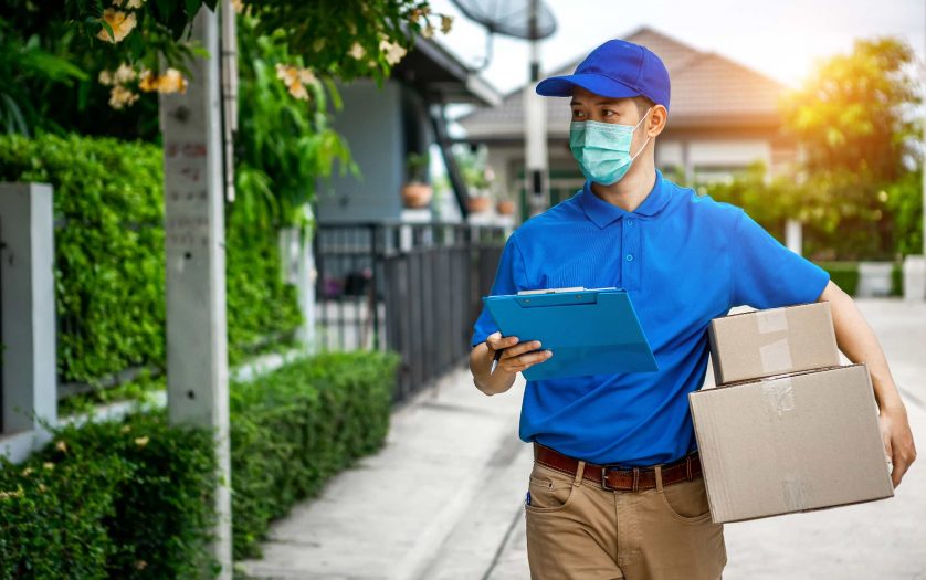delivery man in blue t-shirt carrying parcel box and document to sign in front of customer home.