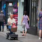A man rides on a scooter for the elderly in Bricklane shopping, London, UK