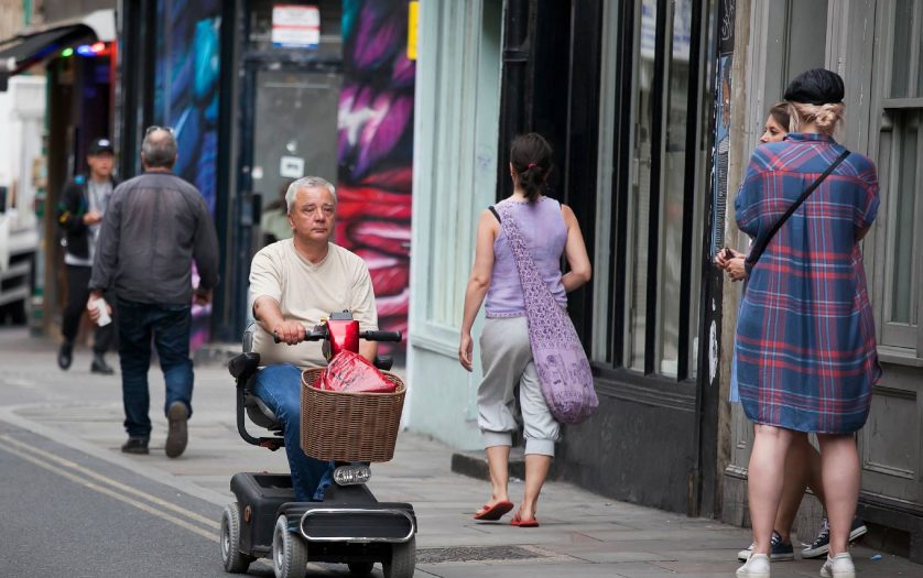 A man rides on a scooter for the elderly in Bricklane shopping, London, UK