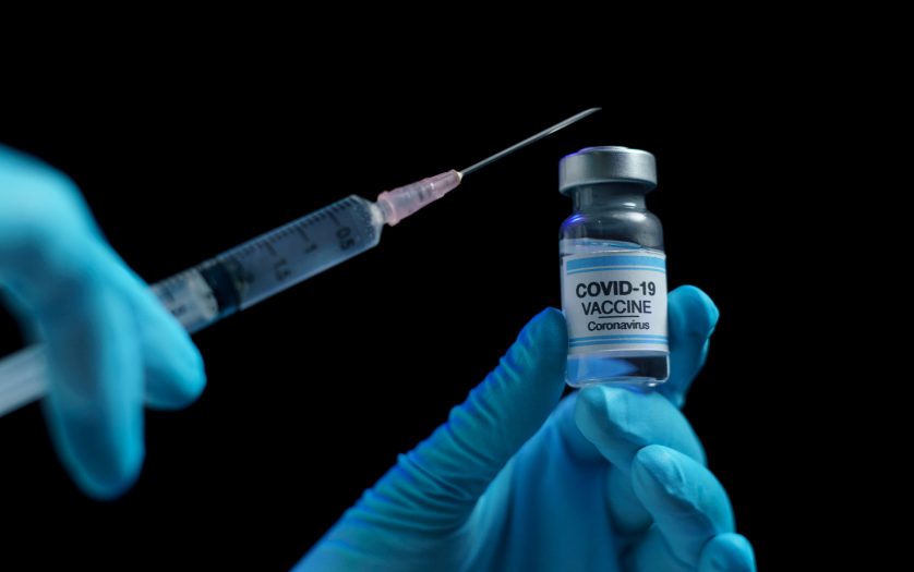 Hand in blue glove holding vaccine and syringe injection for prevention, immunization and treatment from corona virus infection