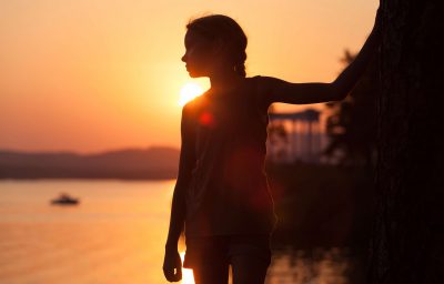 little girl standing on the beach at sunset time.