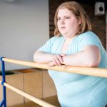 obese young woman standing at bar looking pensively at window