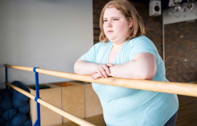 obese young woman standing at bar looking pensively at window