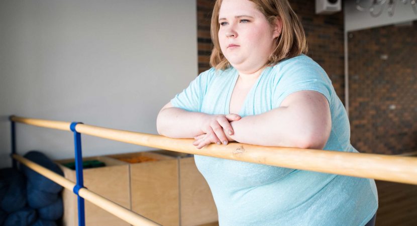 obese young woman standing at bar looking pensively at window