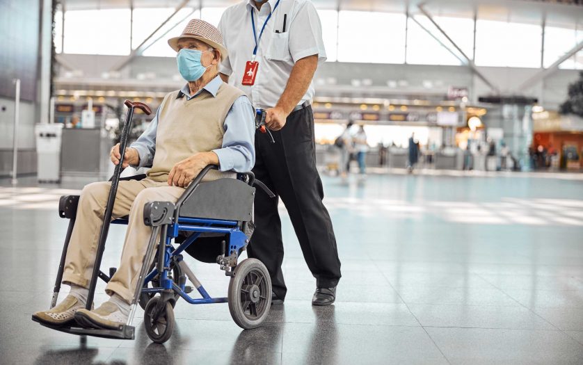 Airport worker rolling a old man in wheelchair