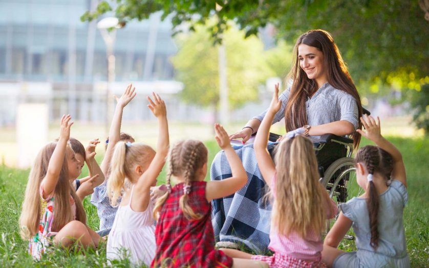 teacher with disability conducts a lesson with children in nature
