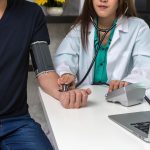 Closeup of Doctor checking man patient arterial blood pressure on the working room in clinic.