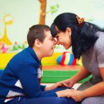 portrait of cheerful mother and her beloved son with disability