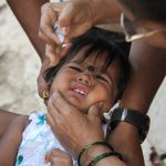 Young child cries while taking polio drops during national polio immunization drive in asia