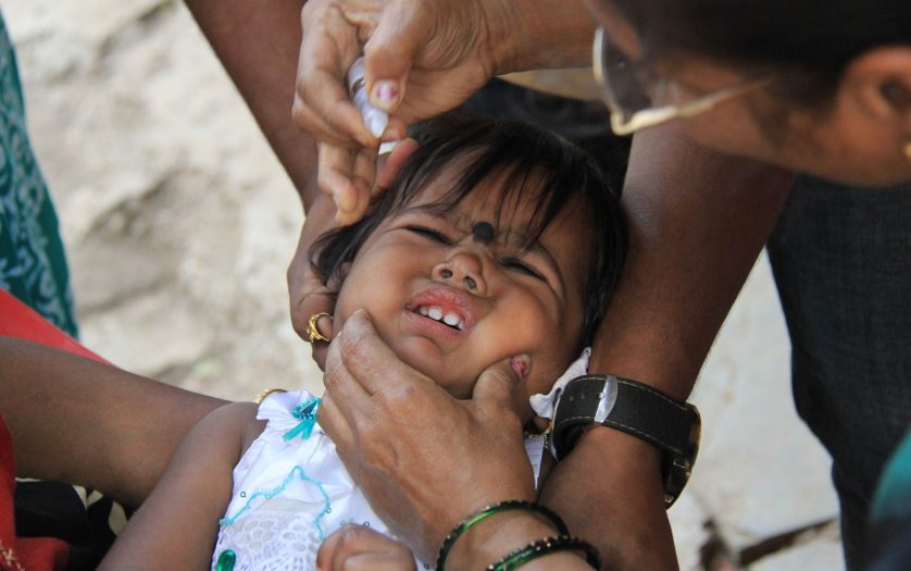 Young child cries while taking polio drops during national polio immunization drive in asia