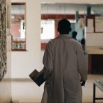 African doctor in white medical gown walking through the hospital lobby in village in Africa.