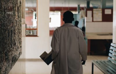 African doctor in white medical gown walking through the hospital lobby in village in Africa.