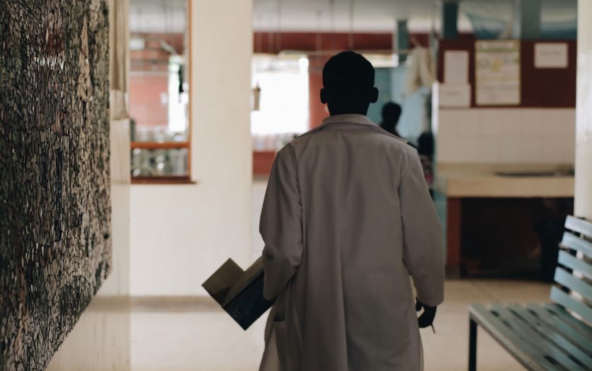 African doctor in white medical gown walking through the hospital lobby in village in Africa.