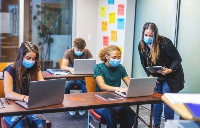High School Students wearing masks and using computers in a classroom with social distancing measures