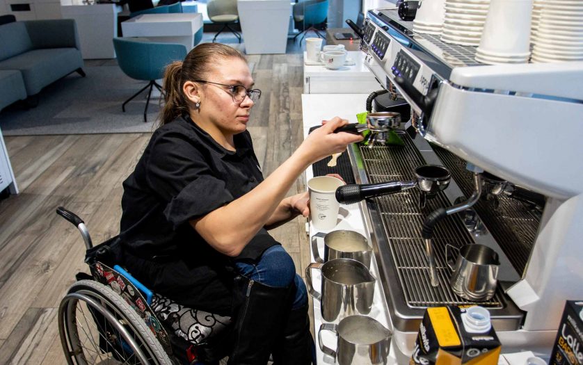 Wheelchair disabled person works as a barista in an inclusive coffee shop.