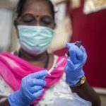 A medical worker prepare an injection of vaccine during a vaccination drive at a community healthcare center.