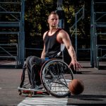 Basketball player in a wheelchair plays on an open gaming ground.