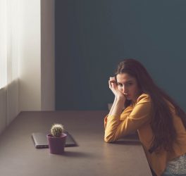 Sad lonely woman sitting at desk at home and thinking