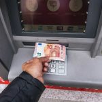 Man`s hand takes out cash euros from Santander Bank in Madrid, Spain