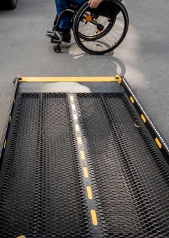 A man in a wheelchair moves to the lift of an accessible bus
