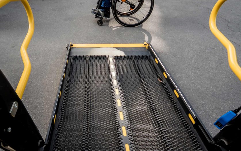 A man in a wheelchair moves to the lift of an accessible bus