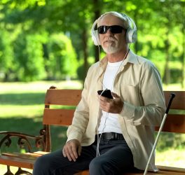 Blind man wearing earphones listening audiobook