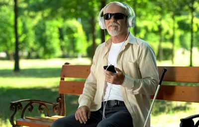 Blind man wearing earphones listening news