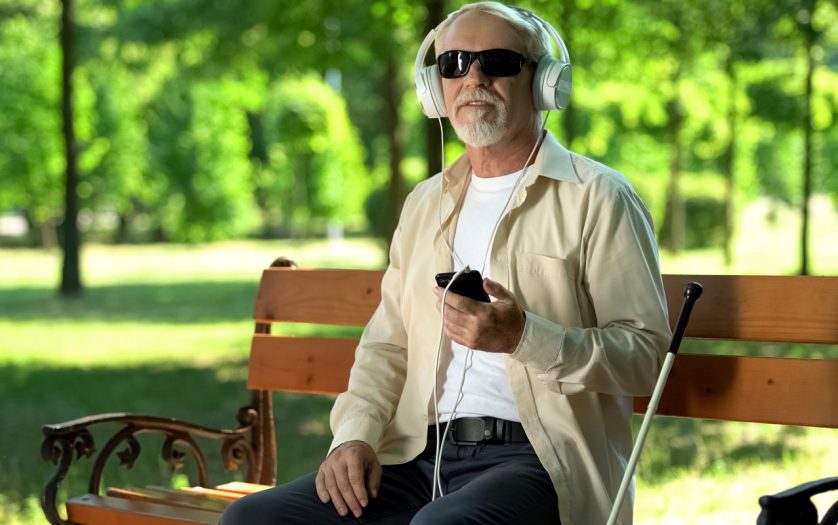Blind man wearing earphones listening news