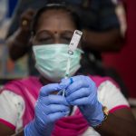 A medical worker prepare an injection of vaccine during a vaccination drive at a community healthcare center.