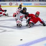 Two ice sledge hockey players battling for puck.