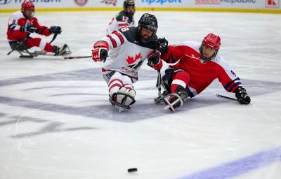 Two ice sledge hockey players battling for puck.