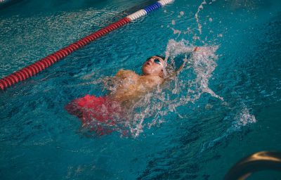 Quadriplegic swimmer in the water. He is using the back stroke technique in the pool lane