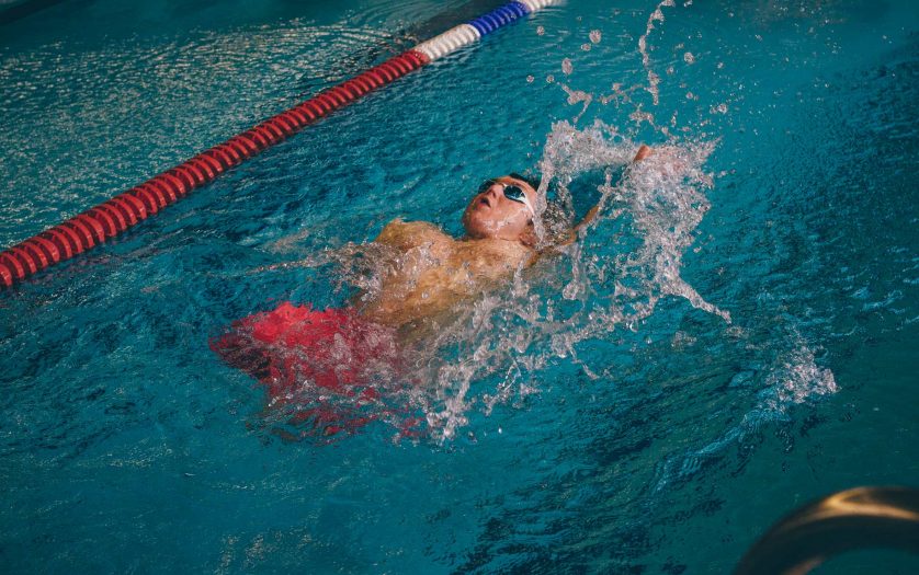 Quadriplegic swimmer in the water. He is using the back stroke technique in the pool lane