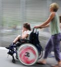 Disabled child in a wheelchair on a city street with family