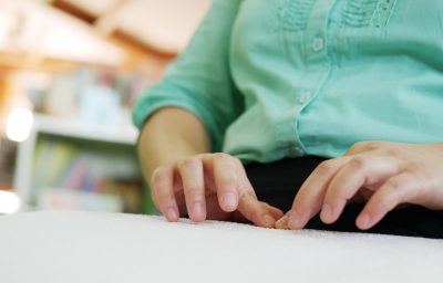 Close-up of blind person woman hands reading Braille
