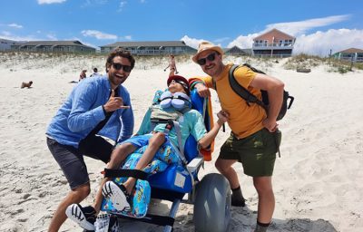 A wheelchair user with smiling people looking at camera outdoor