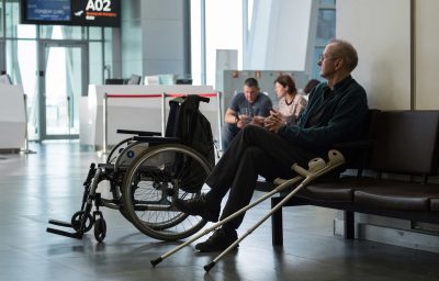 Disabled person in the departure lounge before boarding a plane looks at the scoreboard with a flight schedule