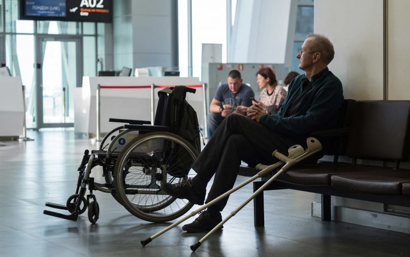 Disabled person in the departure lounge before boarding a plane looks at the scoreboard with a flight schedule
