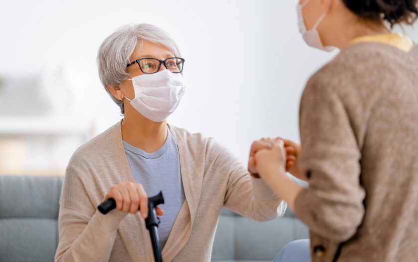 Care worker supporting a senior woman wearing facemasks