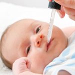 Closeup of mother giving medicine to her newborn baby