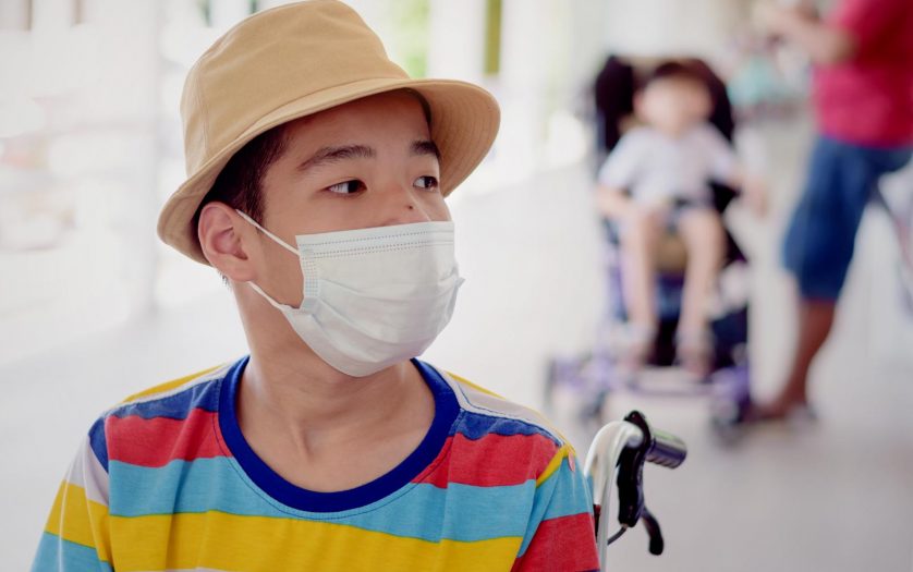 child on wheelchair wearing a protection mask