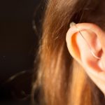 Deaf lady wearing modern digital high technology hearing aid in ear.