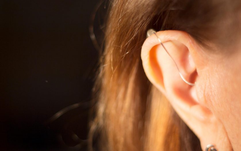 Deaf lady wearing modern digital high technology hearing aid in ear.