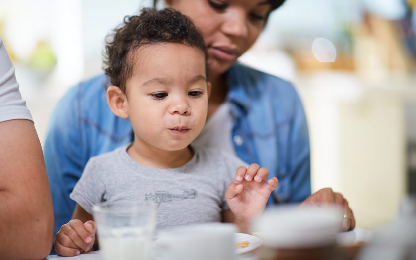 Adorable toddler eating on hands of mother