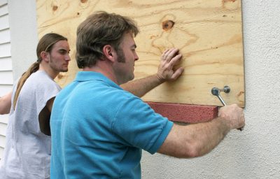 A father & son preparing for a hurricane by putting plywood over the windows