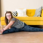 teenager girl with Down syndrome sitting on twine on the floor at home